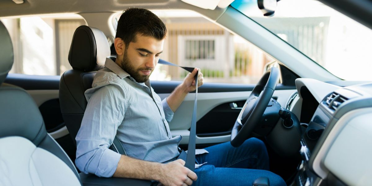 A responsible driver fastens his seatbelt inside a modern vehicle, symbolizing the importance of safety and preparedness. Just as seatbelts protect against accidents, a vehicle protection plan from CarGuard Administration shields drivers from unexpected repair costs, ensuring financial security and peace of mind.